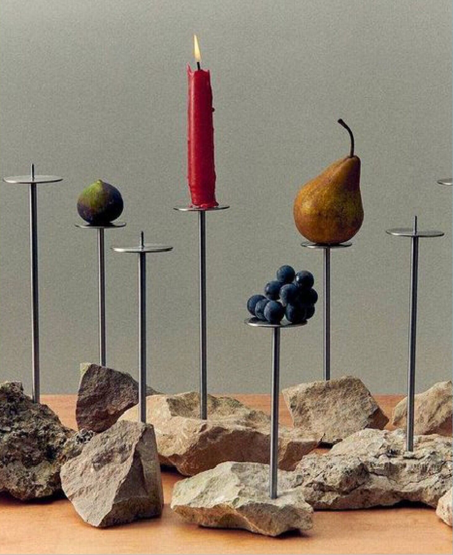 Editorial still life with red candle, pear and grapes on stone